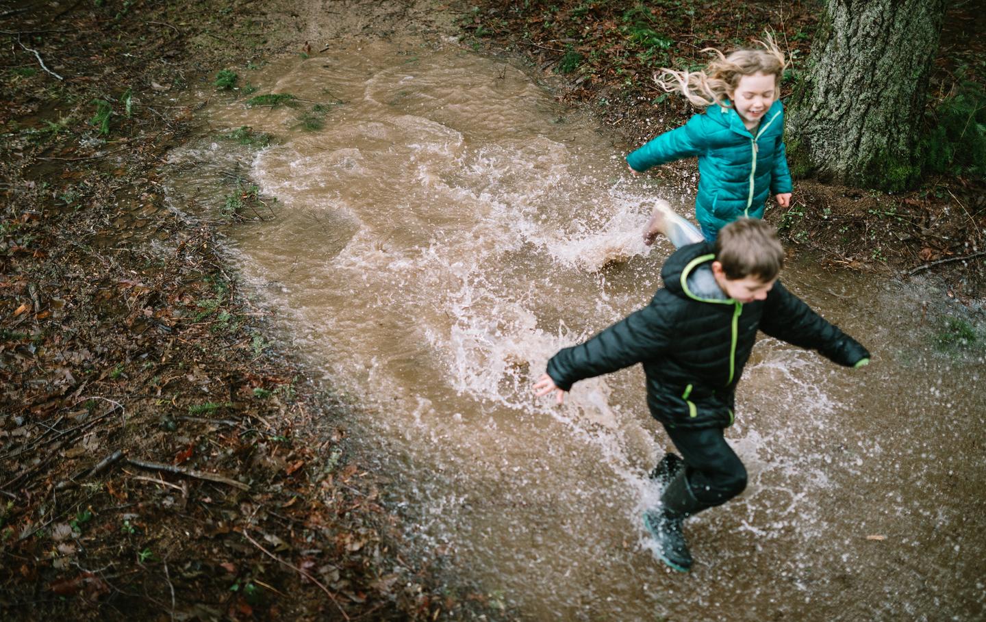 Two kids running through a pond